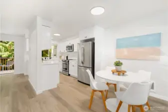 Stylish kitchen and dining area with stainless steel appliances, white cabinetry, and direct access to the outdoor deck.