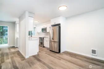Stylish kitchen and dining area with stainless steel appliances, white cabinetry, and direct access to the outdoor deck.