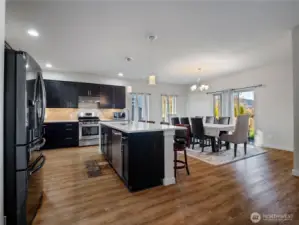 modern kitchen with rich dark cabinetry, quartz countertops, a full-height backsplash, and stainless steel appliances, perfect for both everyday meals and entertaining.