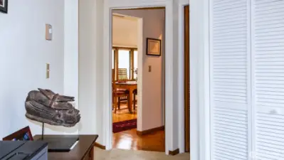 Looking from side room in primary through hallway with half bath to DR. Door to primary full bath with laundry to far right of middle.