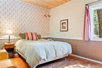The primary bedroom is off the foyer and features beadboard and vintage wallpaper.