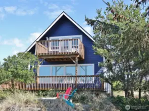 Rear view of this well-maintained Beach-style cottage surrounded by natural landscaping.