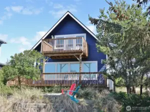 Rear view of this well-maintained Beach-style cottage surrounded by natural landscaping.