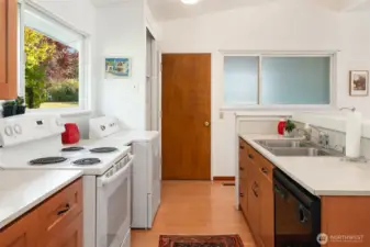 Galley kitchen with a view of the great room and the secret entry garden. Door to the "garage" is at the end. Opaque windows allow more light but block views of the utility space.