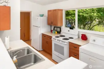 Another view of the kitchen showing door to storage closet/pantry through entry hallway. Newer cabinetry is well-made and in great condition.