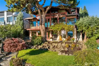 Framed by lush landscaping and soaring evergreens, this striking Northwest contemporary showcases walls of glass, expansive decks, and a seamless blend of indoor-outdoor living. A true bluffside retreat where modern design meets natural beauty.