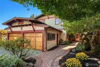 A charming brick pathway winds through lush landscaping to this Craftsman-inspired retreat, where thoughtful details create a welcoming first impression.