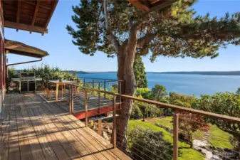 Dappled sunlight filters through evergreens onto this idyllic deck, where tranquil water views create the perfect backdrop for al fresco dining.