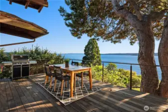 Perched above the Puget Sound, this expansive deck offers the perfect setting for outdoor dining and grilling, with panoramic views framed by evergreens and open sky.