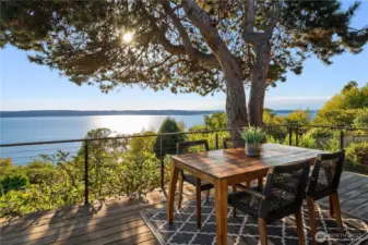 Dappled sunlight filters through evergreens onto this idyllic deck, where tranquil water views create the perfect backdrop for al fresco dining.
