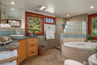 This spa-like bathroom retreat showcases a soaking tub with mosaic tile surround, a glass-block walk-in shower, and lots of natural light for ultimate relaxation.