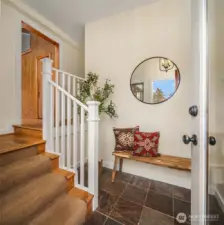 The entrance has slate tile and hardwood floors. Very gracious and inviting! Primary suite is to the right, main rooms are up to the left.