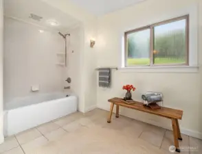 Tub/shower in primary bath. Tiled floors and lovely light fixtures.