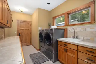 This laundry room has so much counter and cabinet storage with a bench seat and coat storage area near the door leading to the attached 3-car garage.