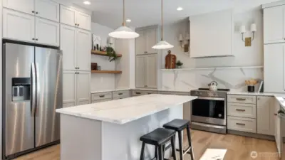 Kitchen has a massive amount of cabinets and quartz counters and backsplash.