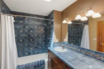 Third bathroom with slate flooring and glaze ceramic artisan tile with extra-long garden tub and double vanity.