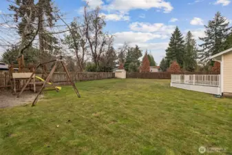 Another backyard view showcasing shed, playset, and spacious deck.