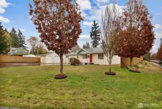 Front corner view highlights abundant parking and detached garage with side work area.