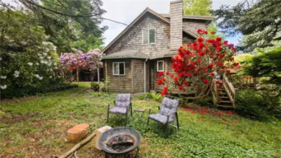 Charming and effortlessly livable, this backyard oasis is where coastal leisure meets cottage-style hospitality. Surrounded by vibrant blooms and mature greenery, the garden lounge features cozy seating around a firepit—perfect for evening gatherings, morning tea, or stargazing under the sky. It’s a space that feels both tucked away and totally at home.