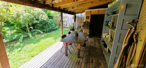 Tucked between the garden and garage, this covered deck creates a versatile outdoor haven—ideal for potting plants, casual gatherings, or simply unwinding under shelter while surrounded by the lush greenery of Nahcotta’s coastal landscape. With rustic wood tones, thoughtful shelving, and seamless indoor-outdoor flow, it’s a functional extension of the home’s charm and character.