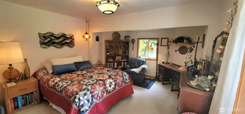 Soaked in golden coastal light and full of personality, this primary bedroom is where charm meets comfort. Wake to views of cottage gardens through oversized windows and feel the warmth of natural wood tones. It’s not just a bedroom—it’s a personal retreat that echoes the soul of the home.