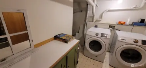 Bright, functional, and thoughtfully tucked away, this laundry room just off the daylight basement features dual front-loaders and plenty of workspace.