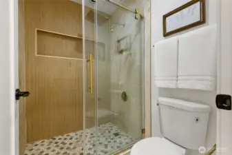stylish tiling and gold accents in this 3/4 bath