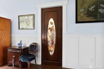 This is a solid wood pocket door featuring the owners custom stained glass leading into the parlor off the kitchen.