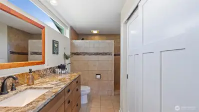 Primary bath has large walk-in shower, closet and heated floors! Note the natural light shining through the transom window.