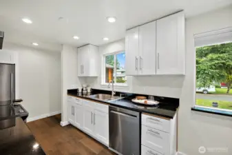 Crisp white cabinets, sleek black counters, and stainless steel appliances make this kitchen feel fresh, functional, and ready for everyday life.