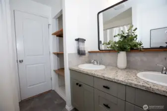 Hall full bath has double vanity, tiled tub surround, and awesome storage tucked behind the door!