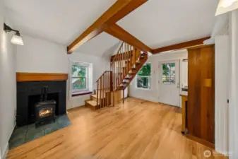 Apartment 7 – Timber-Framed Loft with Artistic Soul  Apartment 7 pairs vaulted ceilings with exposed beams and a custom timber staircase leading to a full-length loft. A cozy gas fireplace anchors the space, while oak floors and built-in cabinetry—crafted from salvaged houseboat wood—add warmth and whimsy. This unit feels like a private artist’s cabin in the heart of the city, offering a one-of-a-kind living experience atop Laurel Gate.