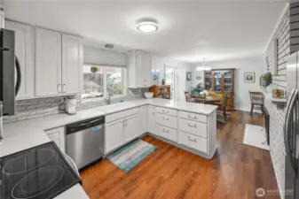 The kitchen has been tastefully updated in crisp, classic white, which never goes out of style or dates itself and the full wall of brick adds a super charming touch- this isn't faux brick, it's the real deal and it is home to the wood burning fireplace located in the informal dining area.