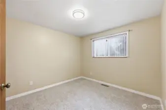 Light-filled additional bedroom with a window overlooking the backyard, ideal for guests or a home office.