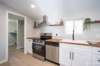 The butcher block countertops, open shelving, and farmhouse sink create a stunning focal point! The doorway to the left leads to the convenient utility and mudroom.