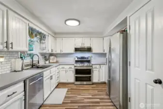 Kitchen showcasing white, farm style cabinetry & stainless-steel appliances