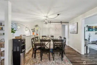 Dining area with sliding barn-style door leading into master bed & bath