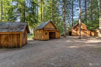 Multiple outbuildings include a storage shed, carport with two additional storage areas, a detached guest cabin with adjacent wax room/work shop. Plus 2 woodsheds filled with firewood.