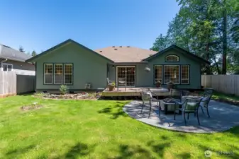Surrounded by lush evergreens and enclosed with a tall wood fence, this outdoor space offers a serene setting ideal for entertaining or quiet evenings at home.