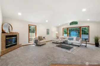The living room features plush carpeting, a cozy gas fireplace with a tile surround.