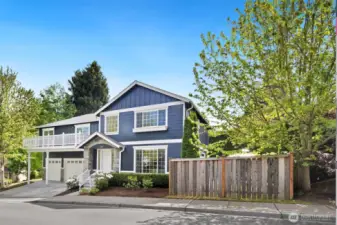 Corner-lot curb appeal shines at this beautifully maintained home, with a navy exterior, stone accents, and crisp white trim that feels timeless and fresh.
