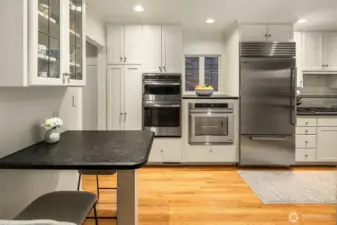 Expansive kitchen with high end appliances and a built in seating area.