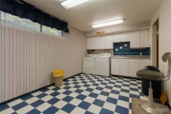 An expansive laundry room enjoys a utility sink and plenty of storage. Washer and dryer remain with the home.
