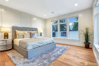 Spacious primary suite with custom millwork wall trim, rich hardwoods, and room for a seating area.
