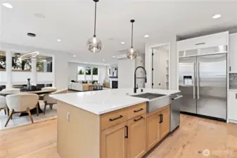 The oversized center island is the true hub of the home, offering generous prep space, seating, and seamless connection to the dining and great room. Warm wood tones, sleek black hardware, and modern globe pendants add layered texture and sophistication, while the open layout keeps the kitchen at the heart of daily living and entertaining.