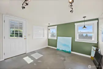 Attached studio space with separate entrance. Complete with accessible outlets, lighting, shelving and a robust exhaust fan previous used as an art studio). Concrete flooring leaves you with many possibilities for use.