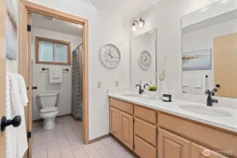 Full hallway bathroom with double vanity, Corian counters, new quartz sinks, skylight and tile floor.