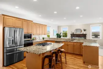Gourmet kitchen with granite slab counters, on point tile backsplash with deco accent, gas cooktop island, stainless-steel appliances, walk in pantry and built in work desk.