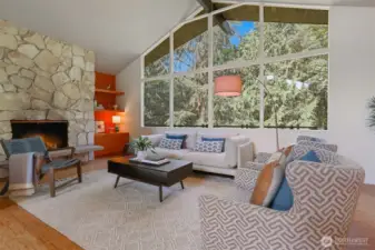 Cathedral ceilings and an expanse of windows curate an ever-changing tableau of your private forest. A traditional hearth pairs with a custom-built-in.