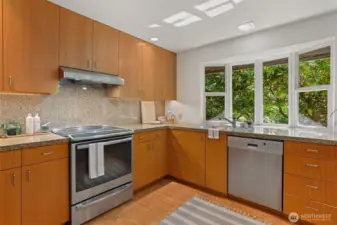 Custom white oak cabinetry with brushed nickel accents, granite counters, Bosch induction cooking and stainless-steel appliances.